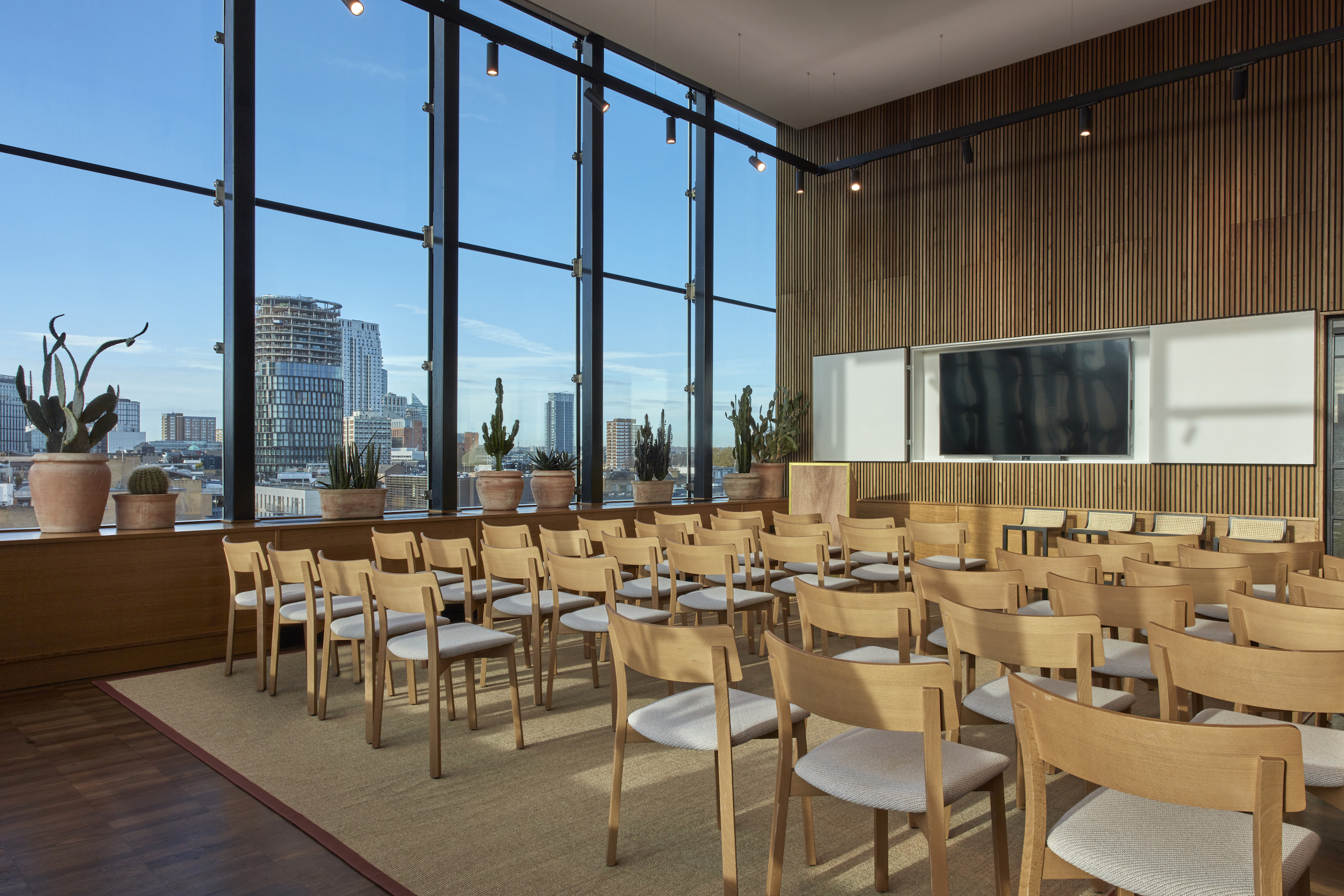 A conference room featuring wooden chairs and a large window allowing natural light to illuminate the space.
