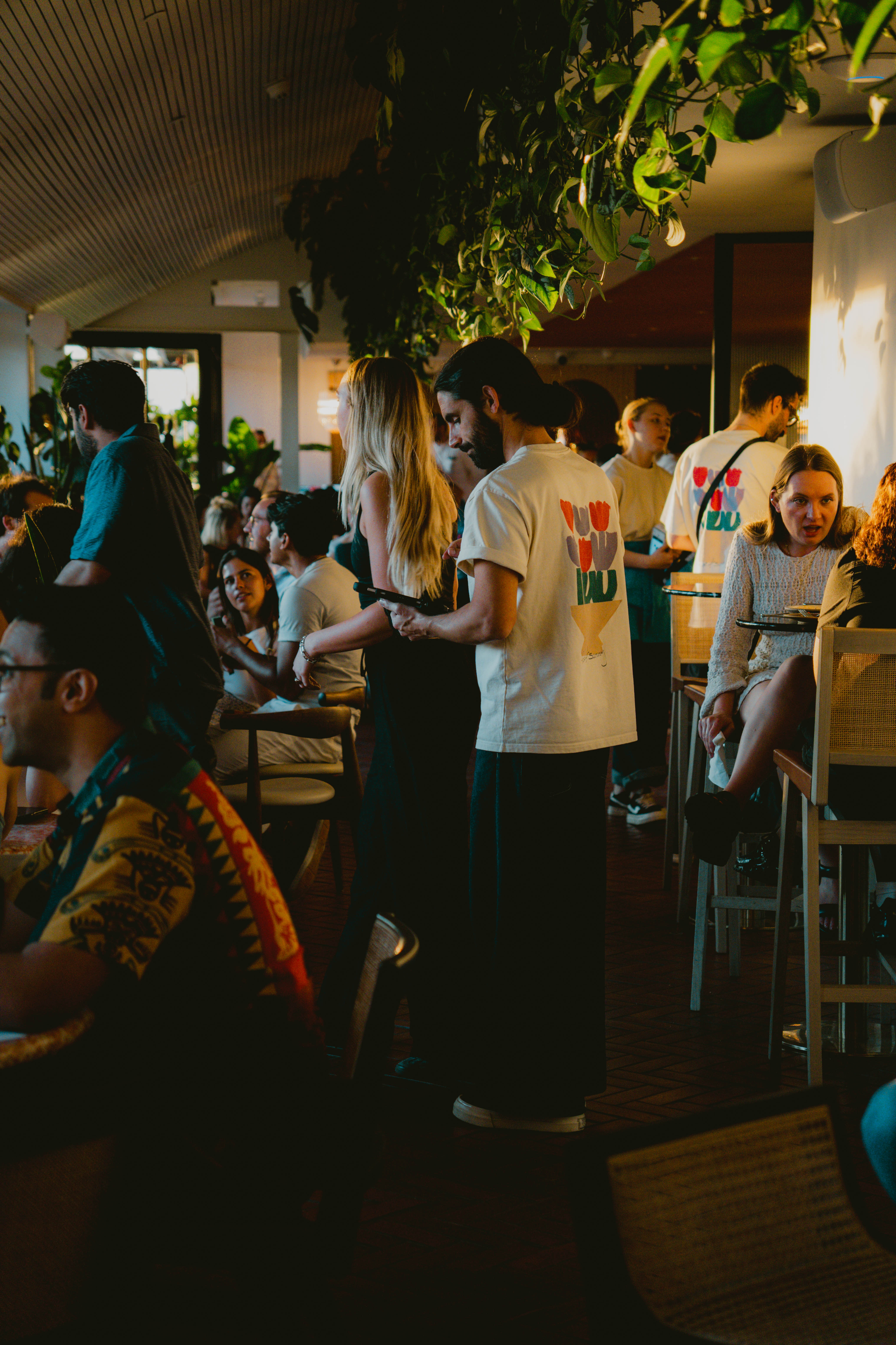 People seated at tables in a restaurant, enjoying their meals and engaging in conversation.